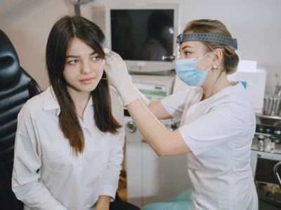 paciente-mujer-consultorio-medico-doctor-mascara-medica-lor-revisa-oidos-mujer_1157-45539